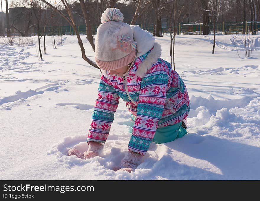 winter portrait of a girl 7-8 years old playing snowballs