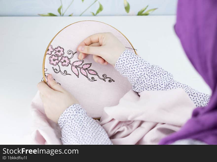 Hand embroidery flowers. Female hands holding hoop, thread mouline. Needlework