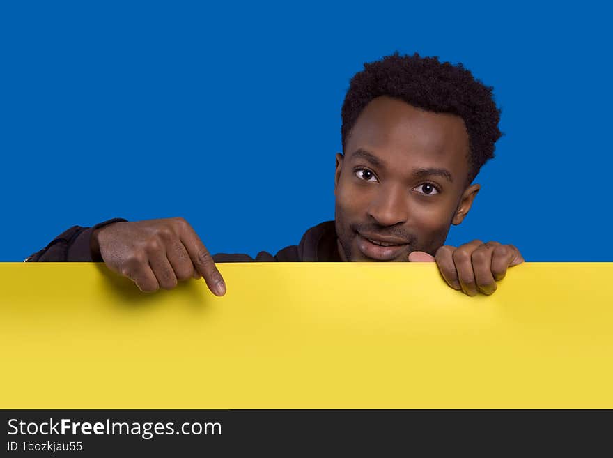 man holding and pointing board copy space background presentation banner poster yellow cardboard on blue background. man holding and pointing board copy space background presentation banner poster yellow cardboard on blue background