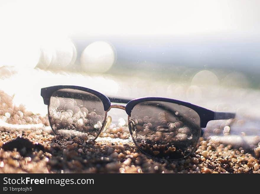 Sunglasses on a sandy beach. Sunset by the sea. Background in bokeh. Vacation at the sea. Flight to the journey.