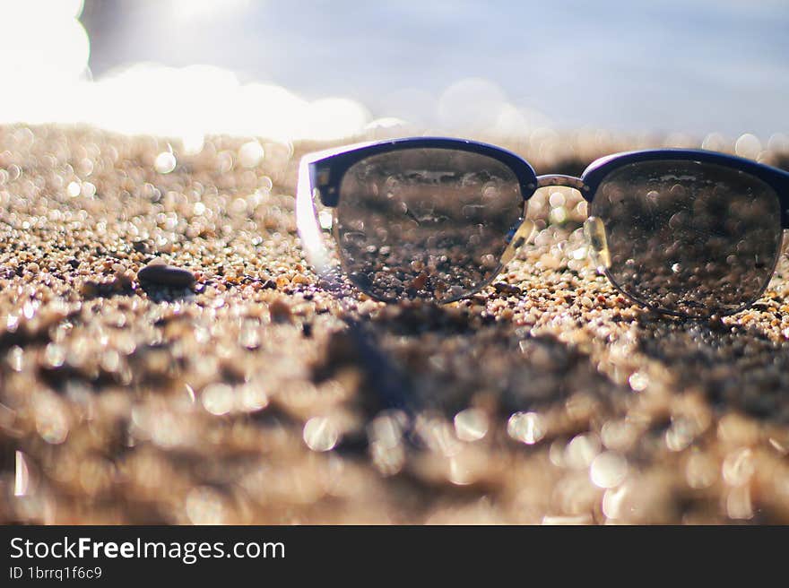 Sunglasses on a sandy beach. Sunset by the sea. Background in bokeh. Vacation at the sea. Flight to the journey.