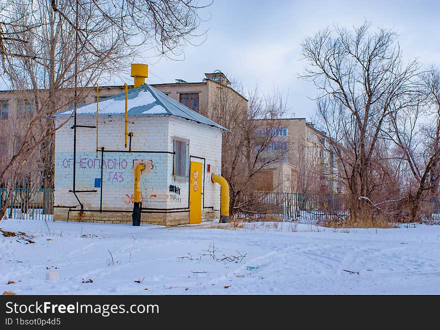 Bare trees, residential buildings, snow, the gas distribution device of Russian gas in action.