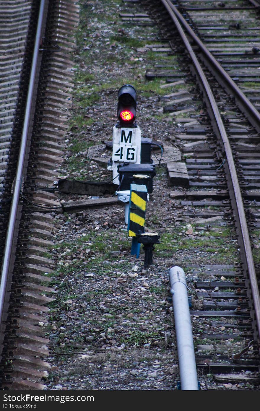 A small railway traffic light shows a red light. Top view of an empty railway.