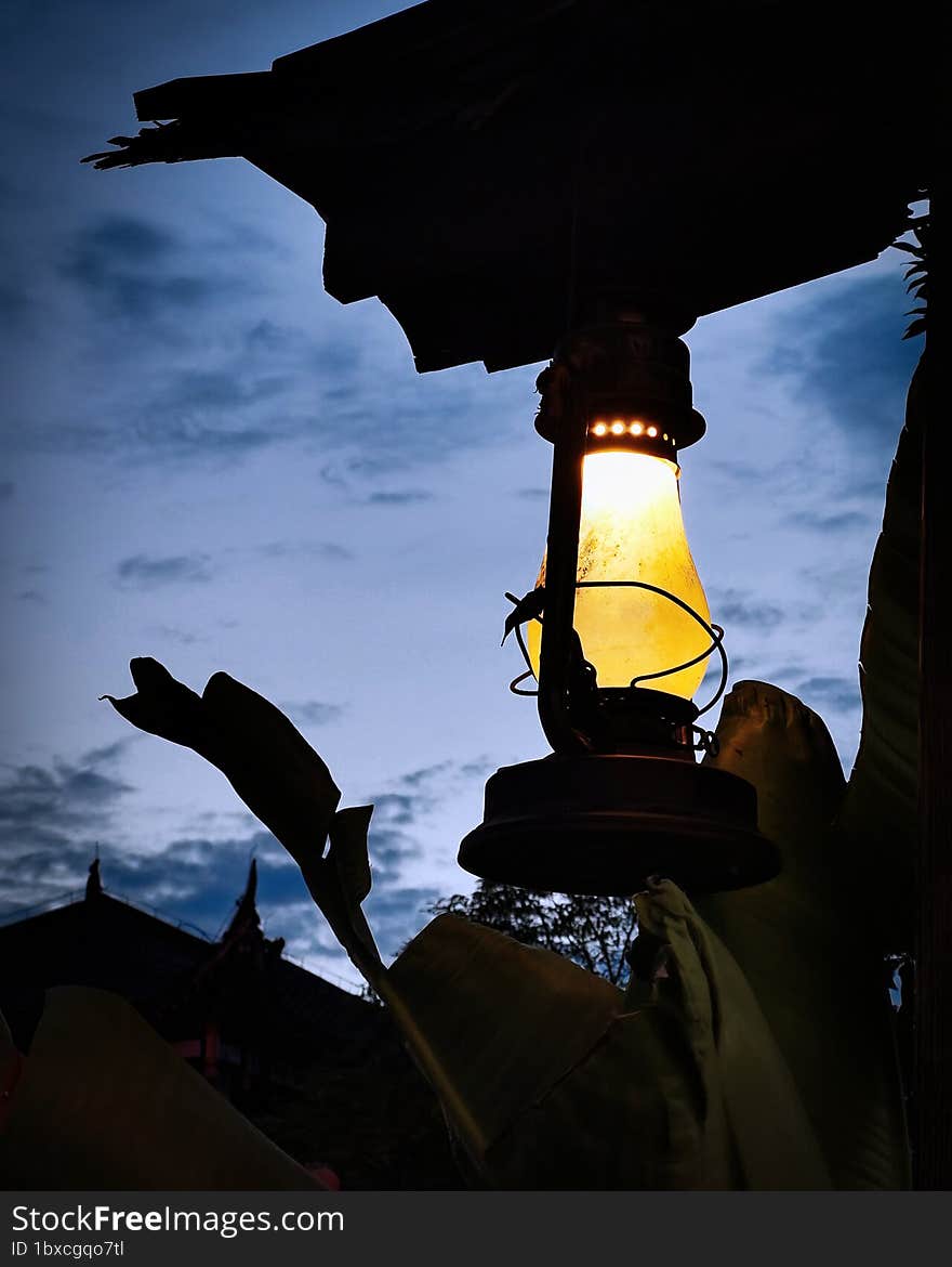 A lantern lit in front of the evening sky.