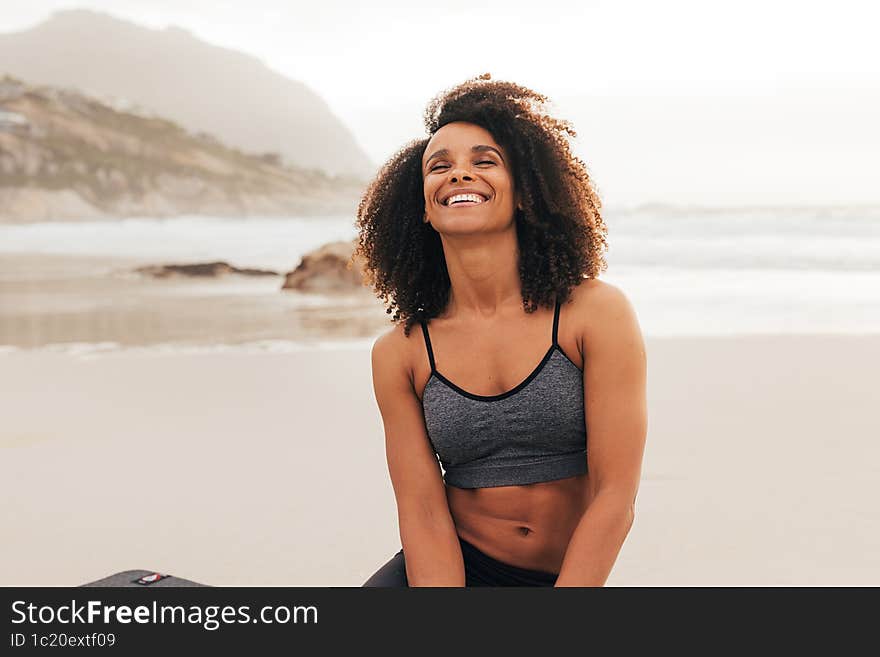 Happy Woman With Closed Eyes Sitting On A Beach After Yoga Exercises