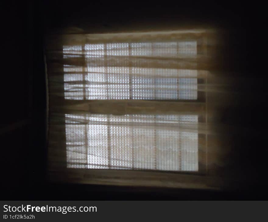 silhouette of a window with blinds in a dark room