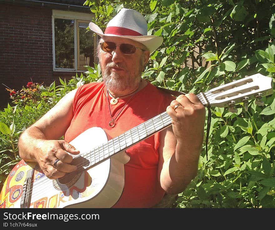 An elderly man plays the guitar