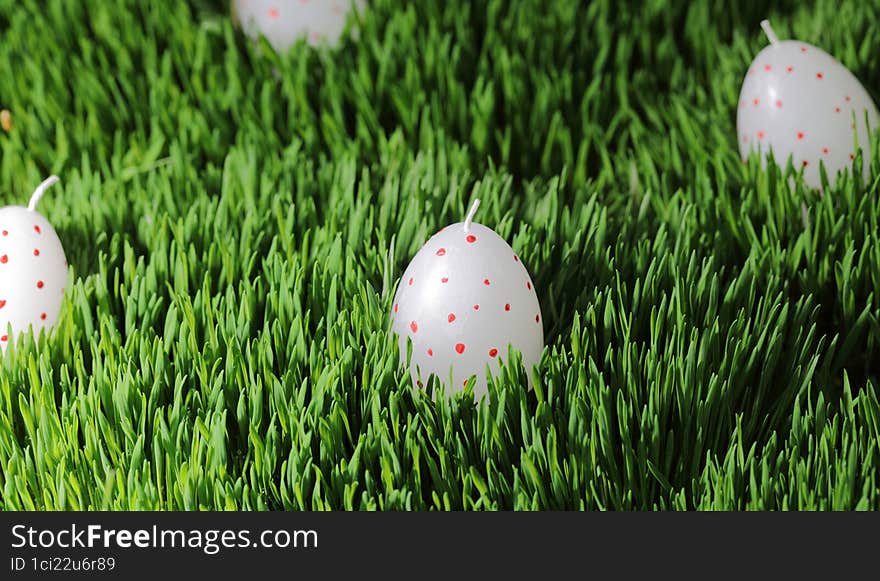 Easter. Eggs on green grass. Holiday day with family. Religious holiday. Candles on a green background. Candles on a larva. Colored eggs for Easter.