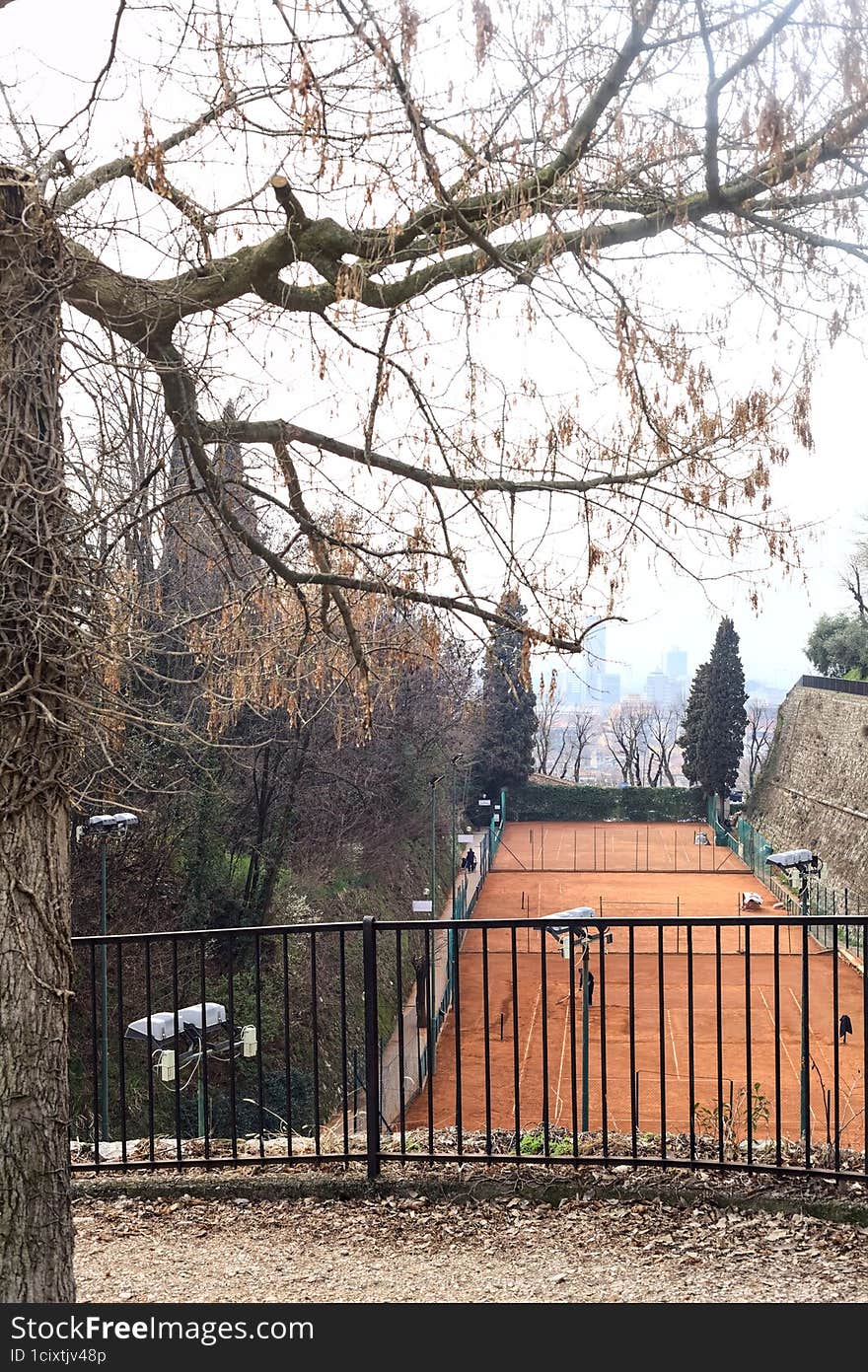 Tennis court in a park of a castle on a cloudy day seen from above