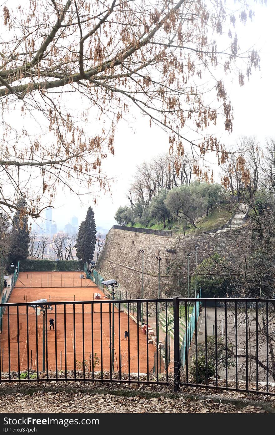 Tennis court in a park of a castle on a cloudy day seen from above