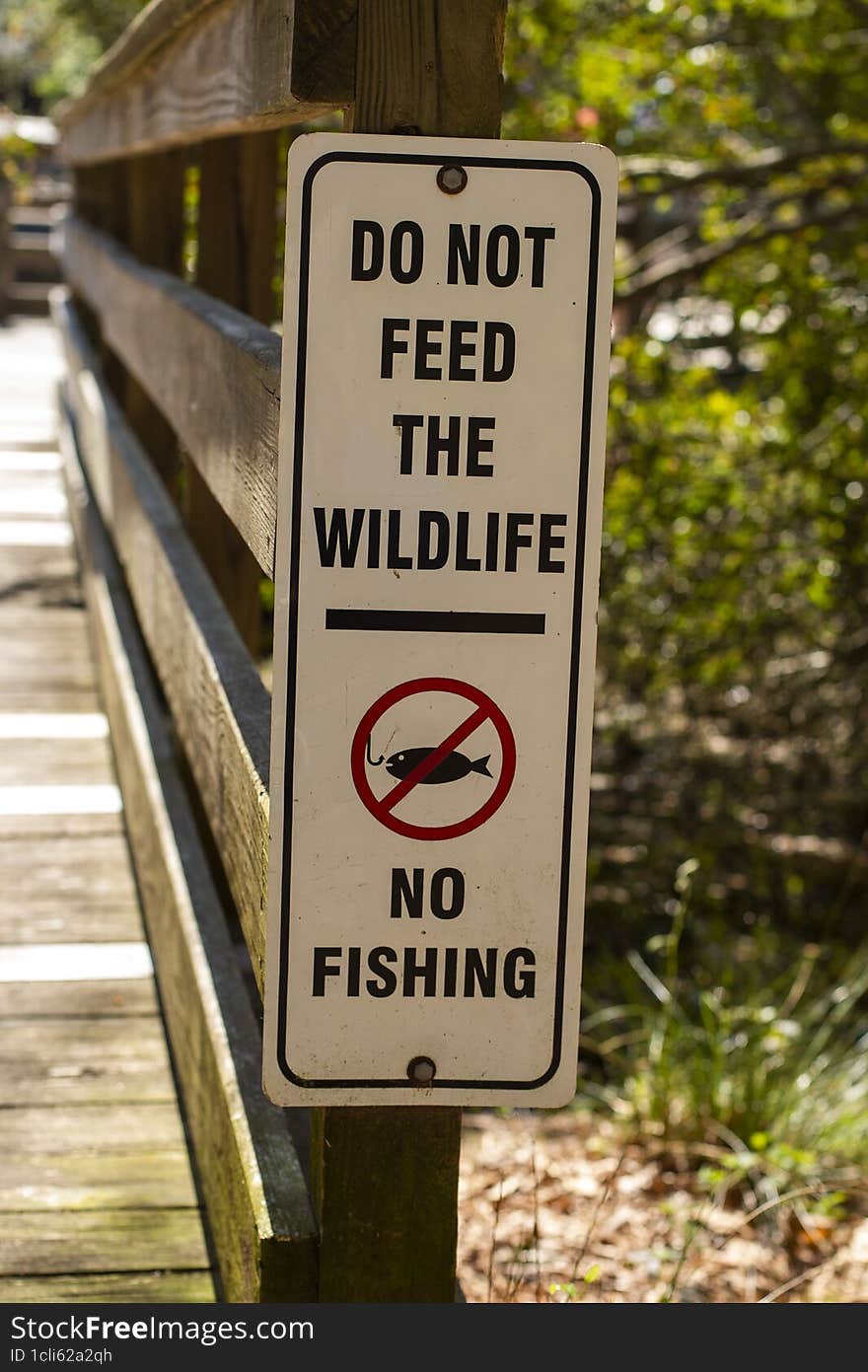 A black and white warning sign that says, & x22 Do Not Feed The Wildlife and No Fishing& x22