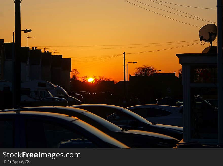 Orange sunset over cars parked on driveways