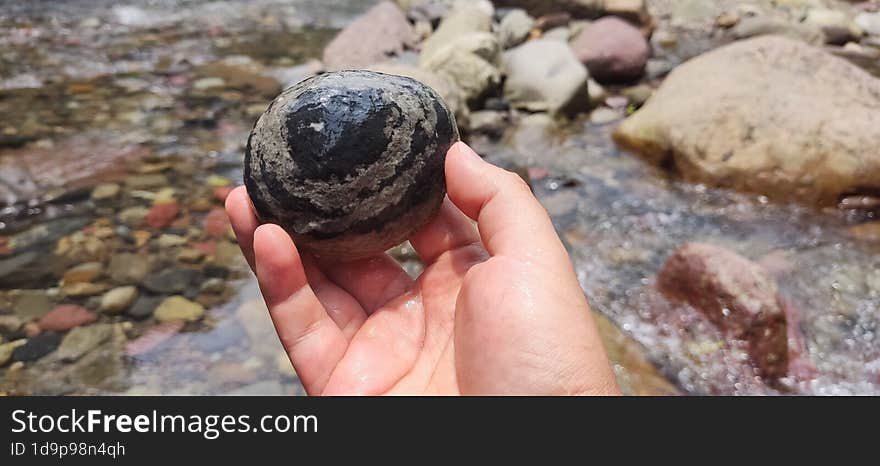 A hand holds a beautiful river rock