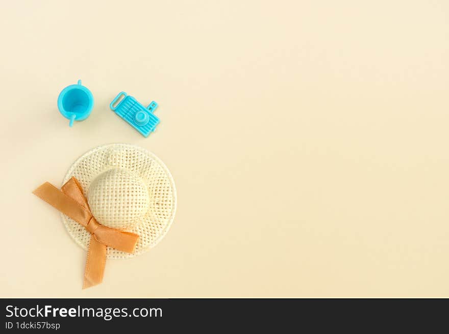 straw hat, toy camera and toy glass with a straw on a pale beige background, vacation content from copy space