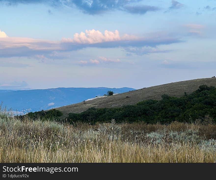 Steppe hills. Evening sky. A mountain on the horizon. Summer sunset.