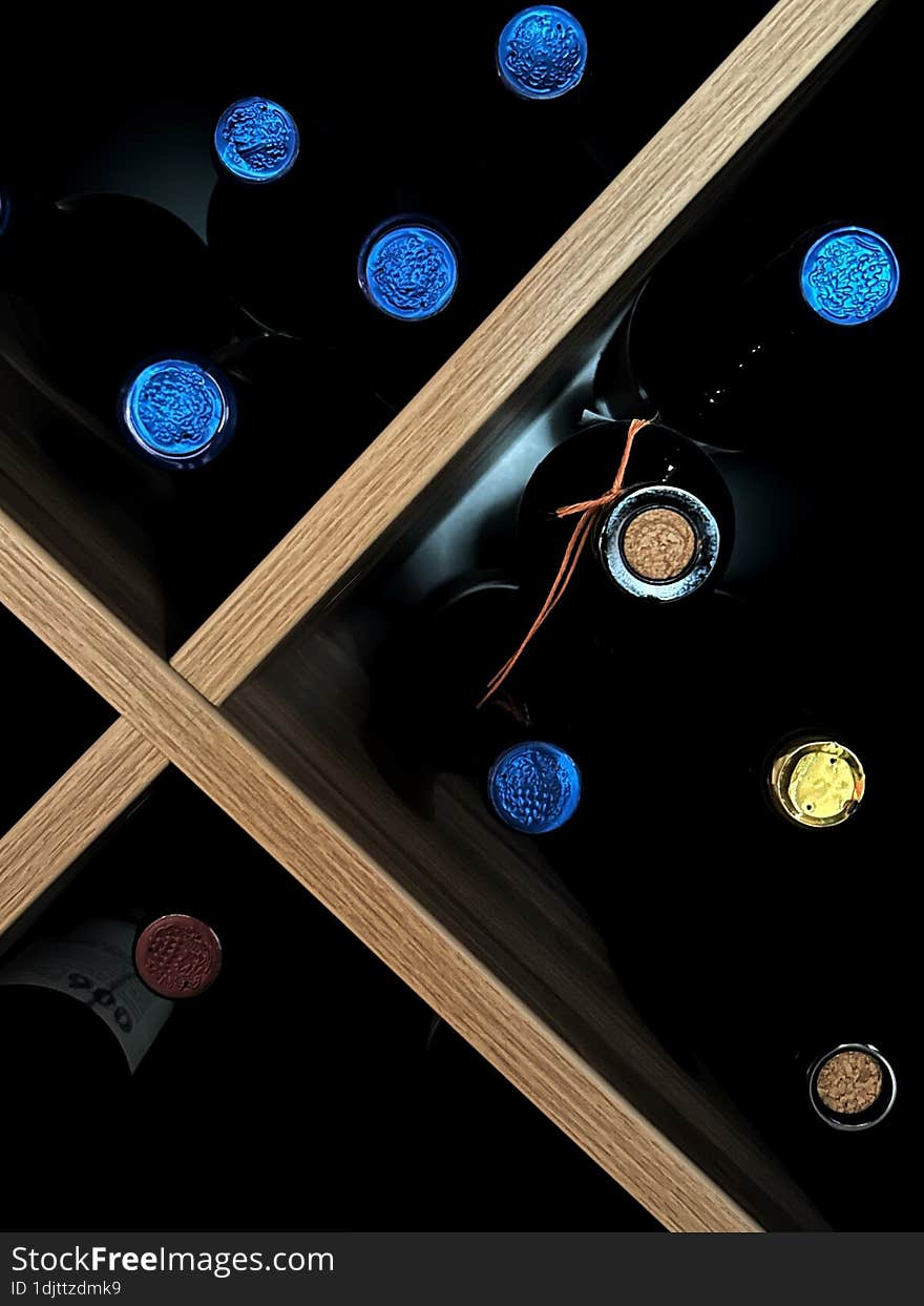 Dark bottles of wine on a wooden shelf