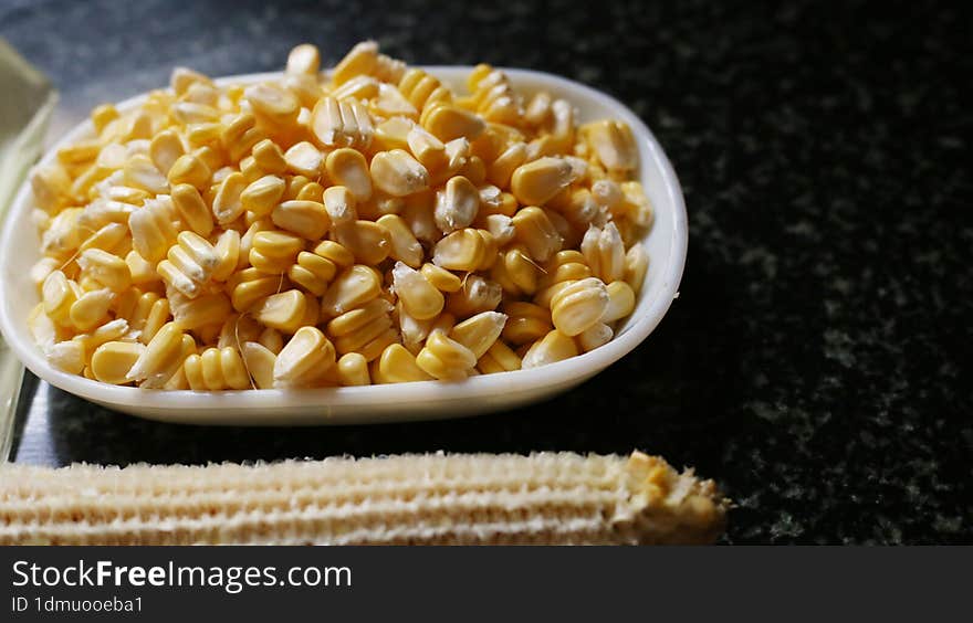 Sweet Corn Chat or Steamed yellow sweet corn, Chat Masala and lemon, served in black dish. Indian Chat or snack.