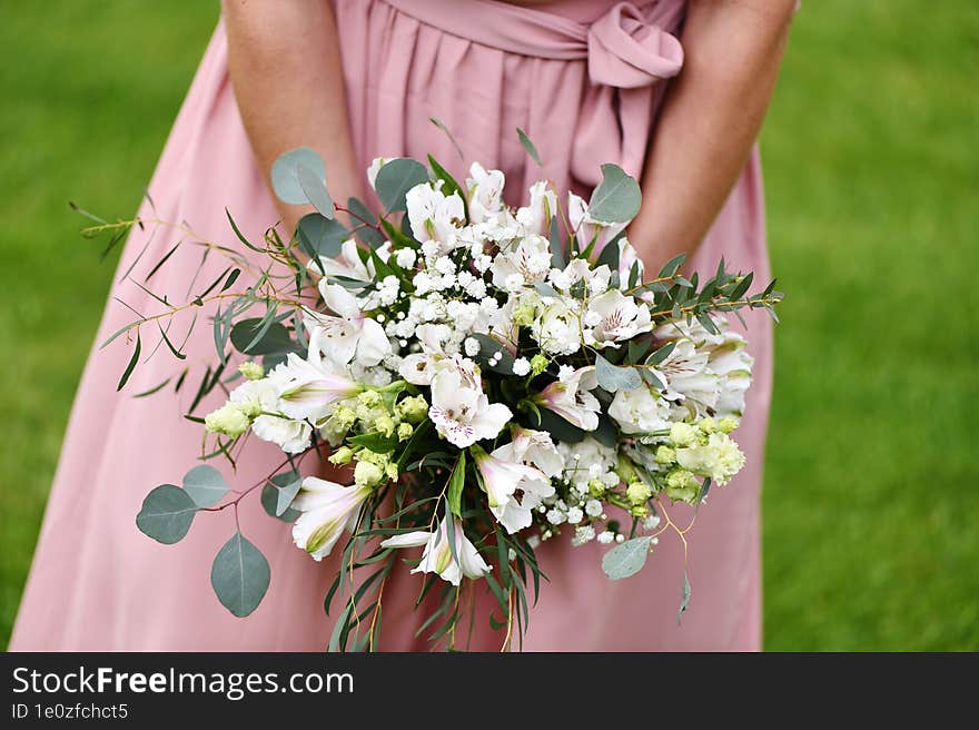 a young girl in a pink dress holds a bouquet of white flowers in her hand. a young girl in a pink dress holds a bouquet of white flowers in her hand