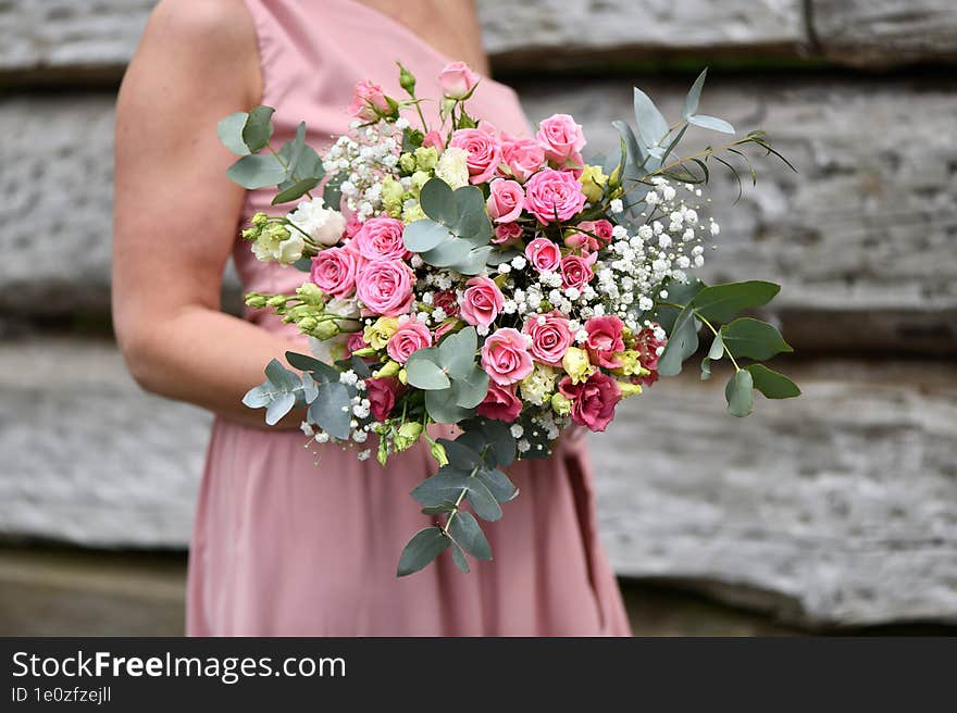 a young girl in a pink dress holds a bouquet of roses and white flowers