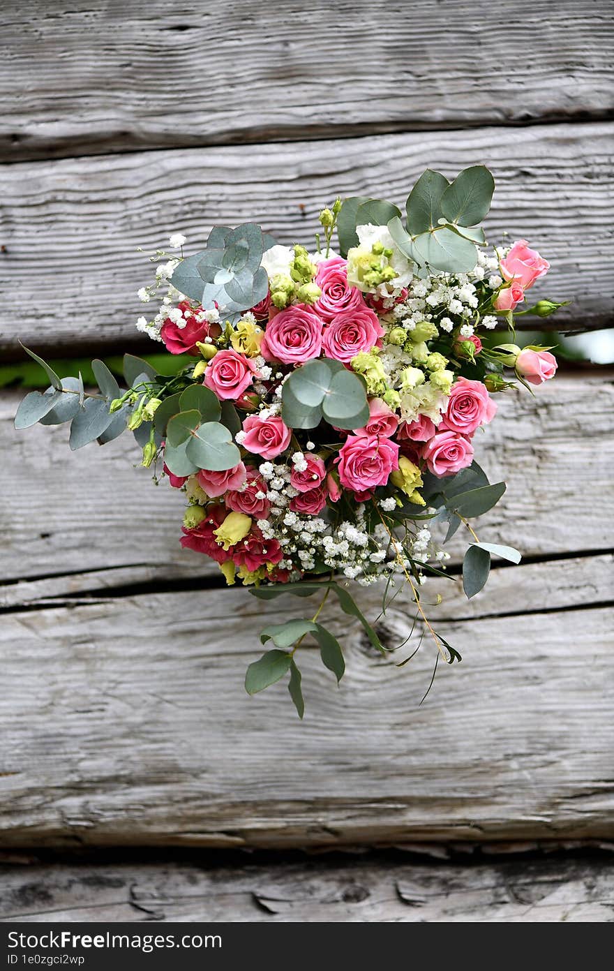 large bouquet of pink roses with white flowers and eucalyptus on a wooden table