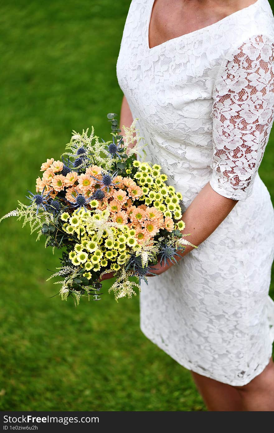 The Bride Holds A Large Bouquet Of Yellow And Orange Meadow Flowers With Eucalyptus