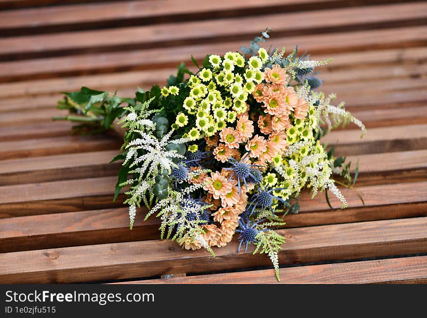 a large bouquet of yellow and orange meadow flowers on a wooden table