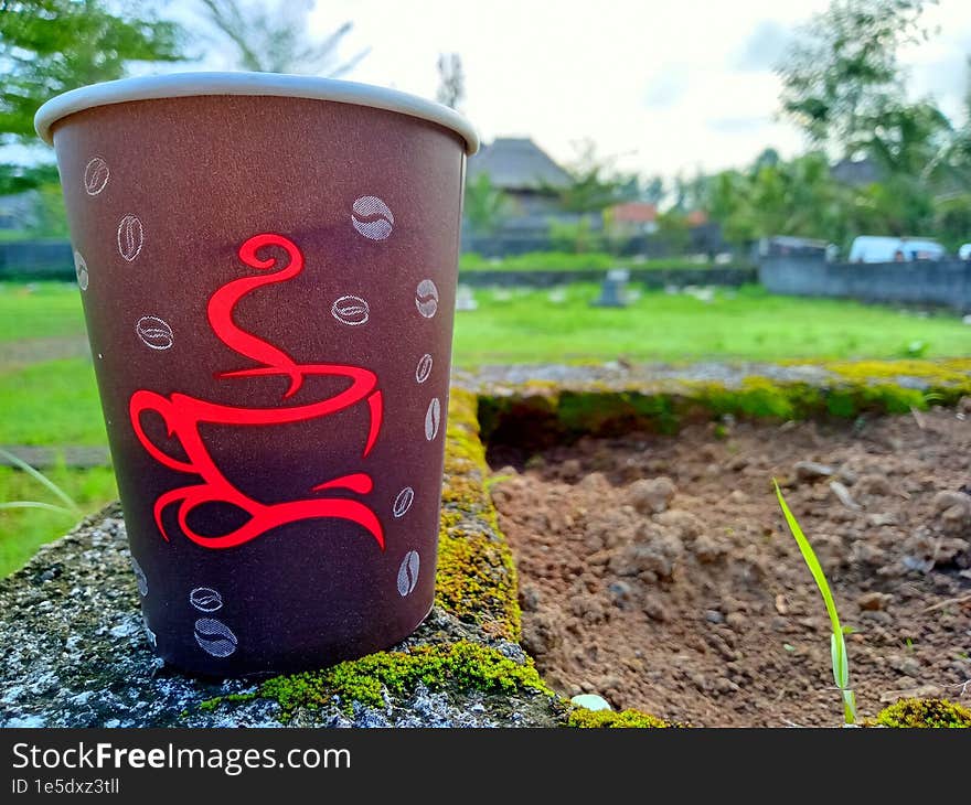 Close Up Photo Of A Paper Cup Filled With Coffee Against A City Park Background In The Morning