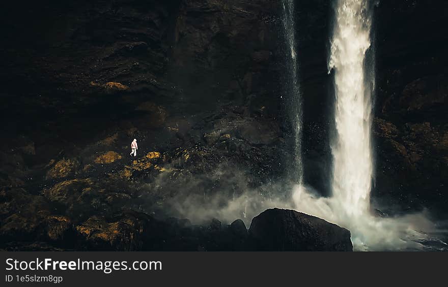 Female tourist walk on pathway visit famous Kvernufoos waterfall landmark. Yellow grass hills on Kvernufoss waterfall. Majestic su