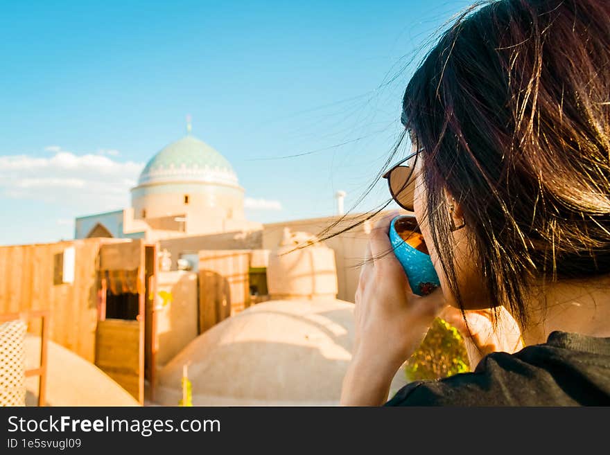 Yazd, Iran - 19th june, 2022: female caucasian tourist drink persian coffee in traditional rooftop cafe relax enjoy panoramic views of old town