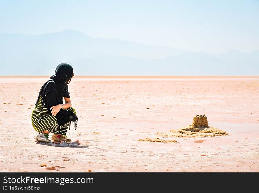 Female traveler tourist sit visiting explore Maharlu pink salt lake shore. Travel destination Iran in Shiraz