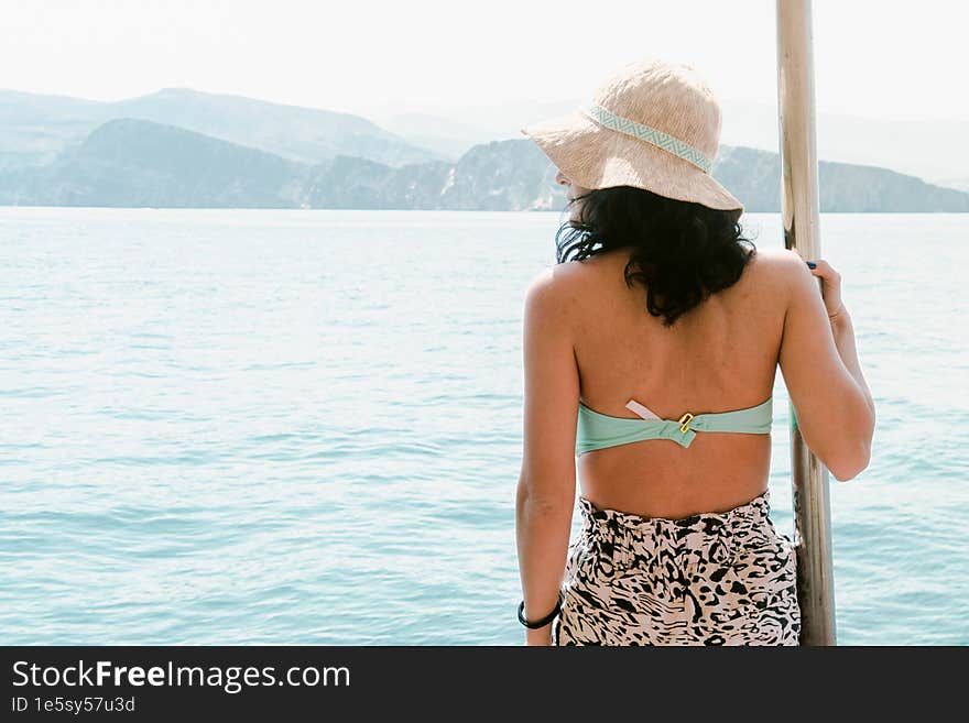 Caucasian woman tourist relax lay on vacation on cruise ship deck enjoy sunny persian gulf panorama with rocky mountains cliffs. Oman holiday destination in middle east.Musandam