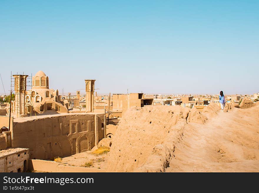 Woman tourist walk on rooftops with panorama from Historic castle in Kashan with city buildings background. Explore iran historica