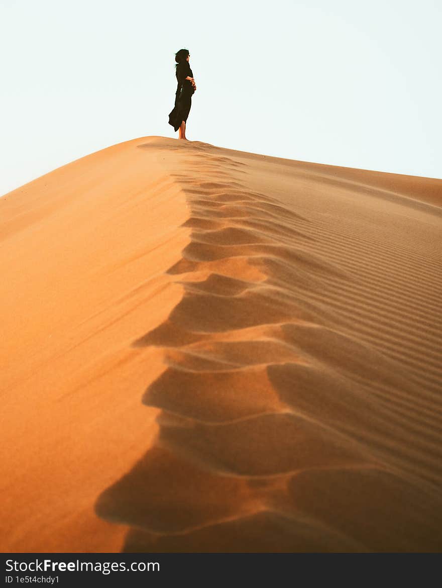 Woman silhouette enjoy sand dunes in desert in sunset blue hour alone. Travel lifestyle and wellness concept. Cinematic wanderlust background