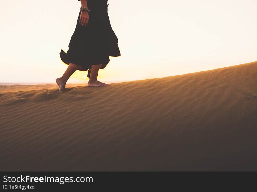 Low angle tracking view beautiful woman in long dress feet follow walk on KAshan desert dunes