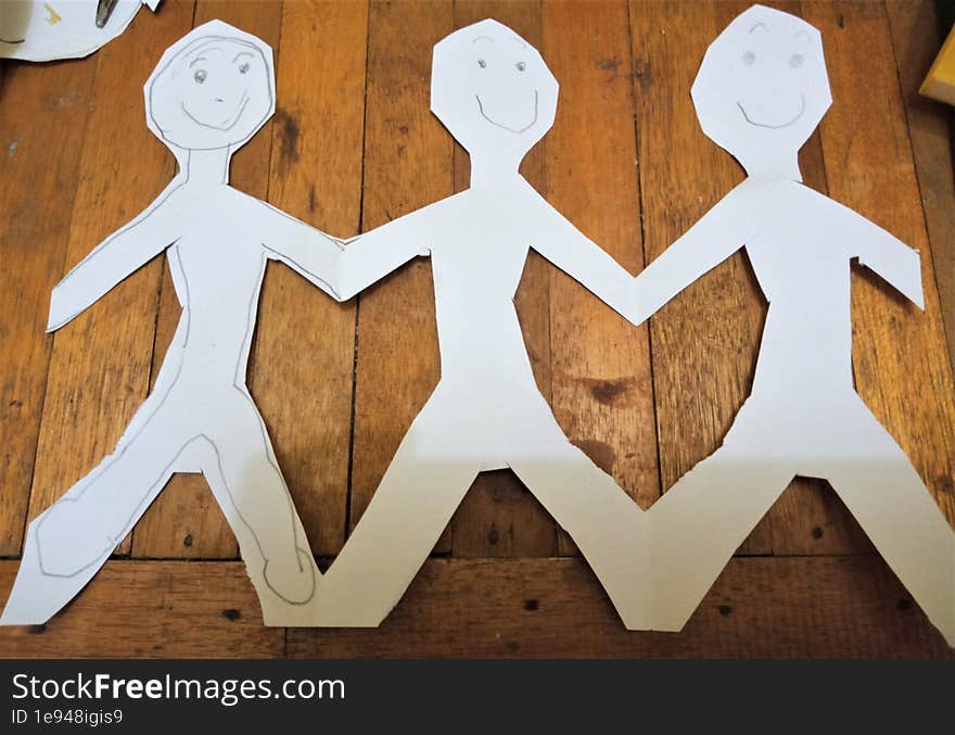 figures cut out of paper are seen holding hands