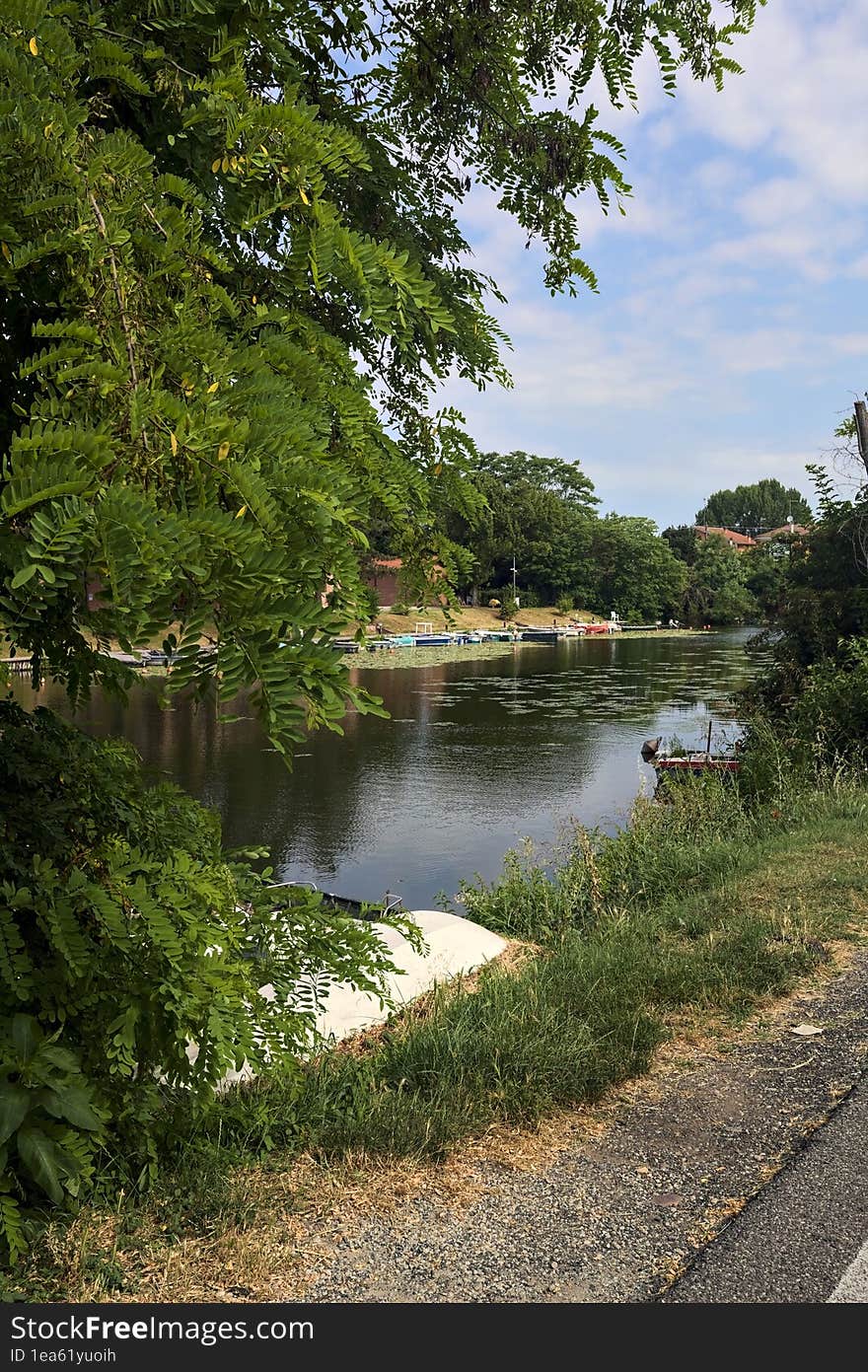 Inlet of a river with moored boats in a park in the italian countryside