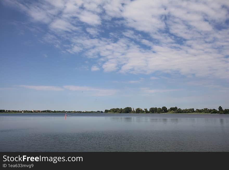 Lake and the opposite shore on the horizon on a summer day in the italian countryside