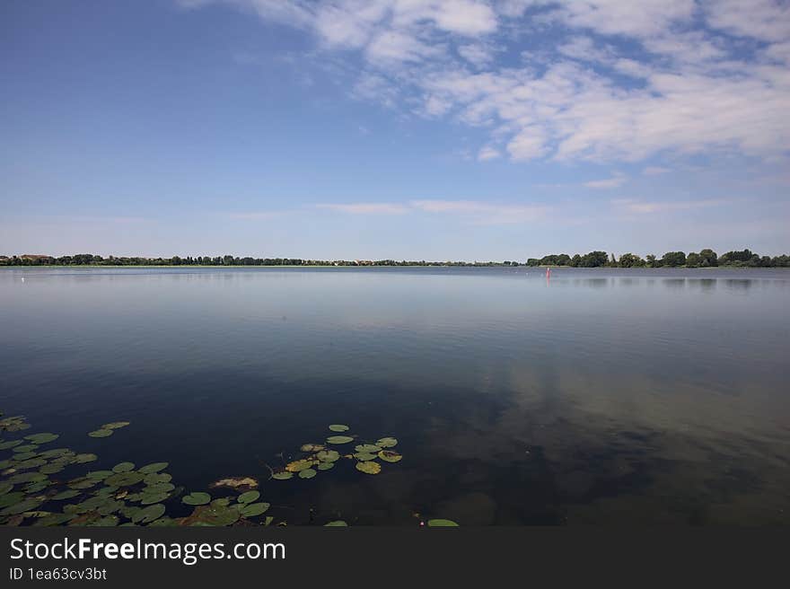 Lake and the opposite shore on the horizon on a summer day in the italian countryside