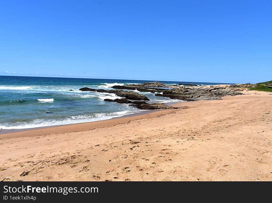 Shoreline With Rocks, Waves And Sand