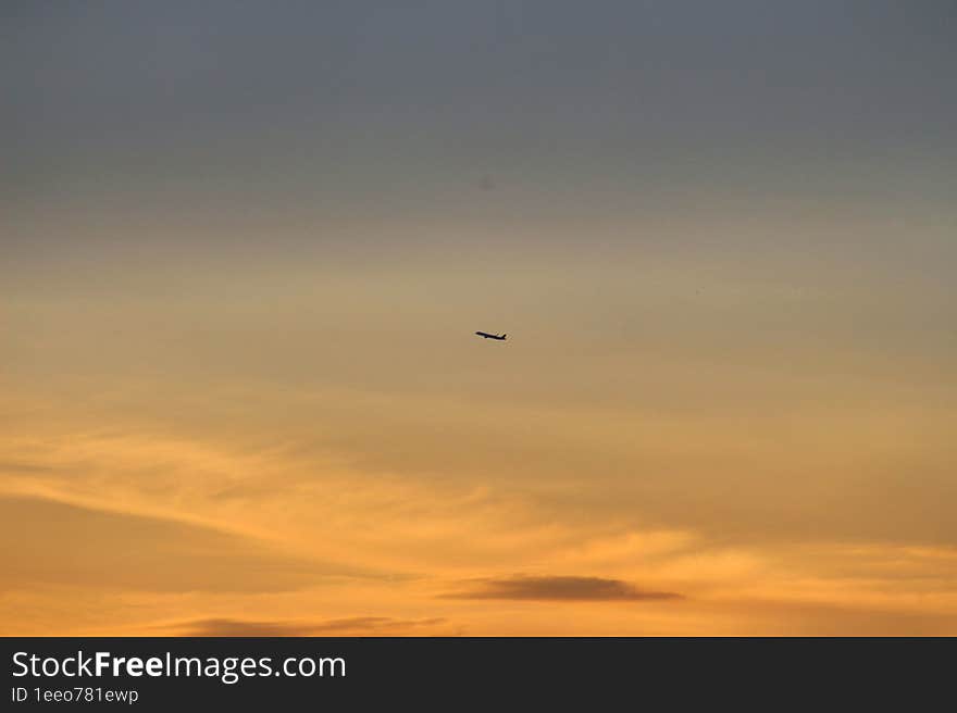 The plane travels among the colorful clouds of the sunset