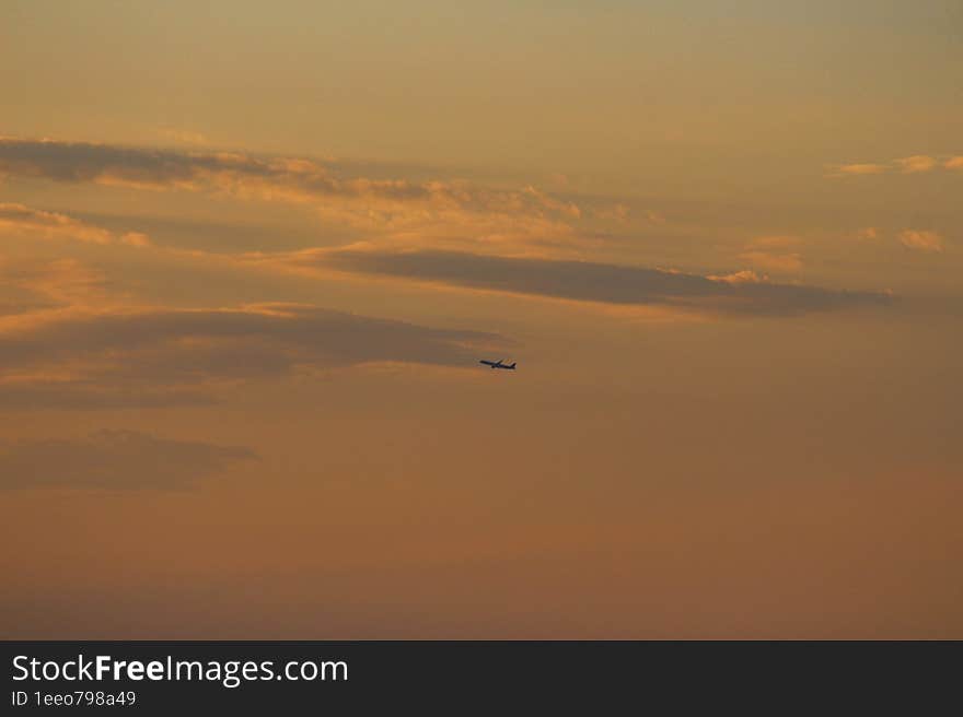 The plane travels among the colorful clouds of the sunset