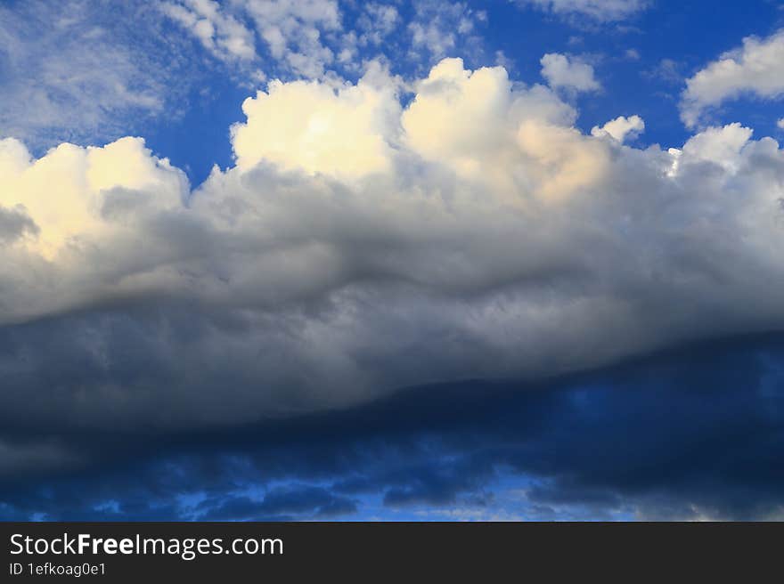 Cumulus large clouds illuminated by the summer sun drift across the blue sky.