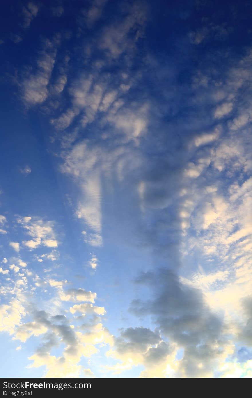 White clouds in the blue morning sky, unusually illuminated by sunlight.