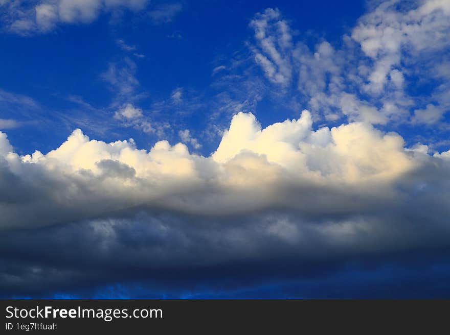 Cumulus large clouds illuminated by the summer sun drift across the blue sky.