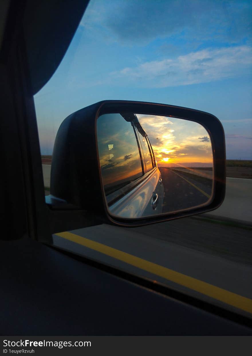 Reflection of the sunset in the rearview mirror of a car