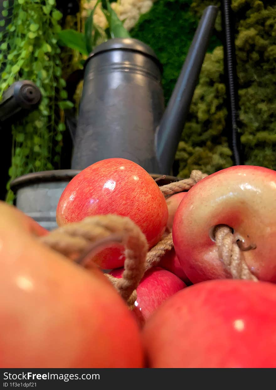 Bright Red Apples With Rope In Front Of Dark Objects And Green Plants