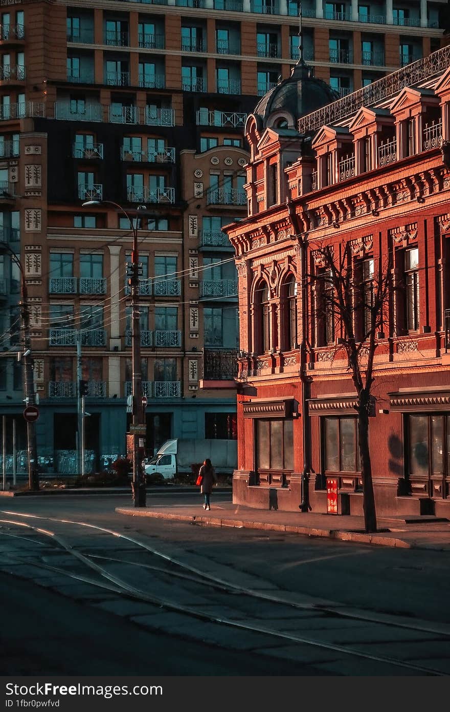 View of city street with tram tracks, and an old red building, evening time, Kyiv.