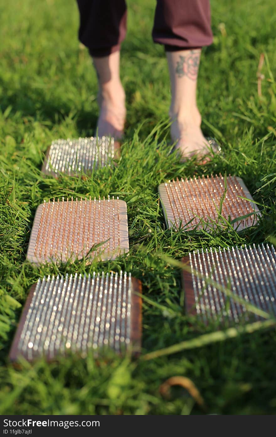 Standing On Nails. Nature. Meditation. The Girl Steps On The Boards With Sharp Zinc And Copper Nails.