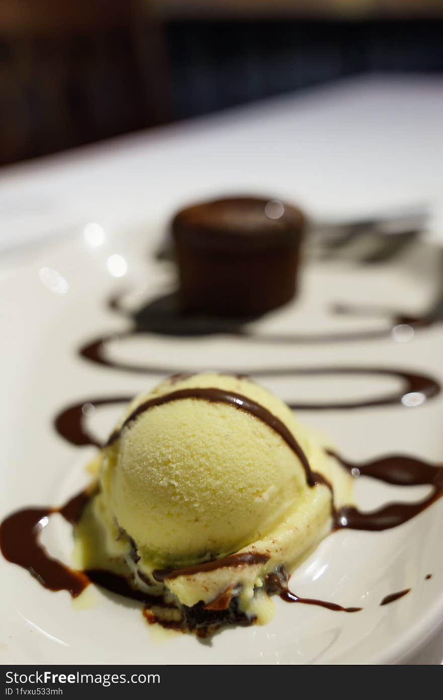 A dessert experience with a tempting plate featuring a generous scoop of creamy ice cream, a decadent brownie, and drizzles of luscious chocolate sauce