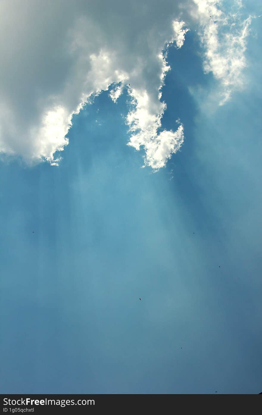 a burst of sunlight with a background of blue sky and dark clouds